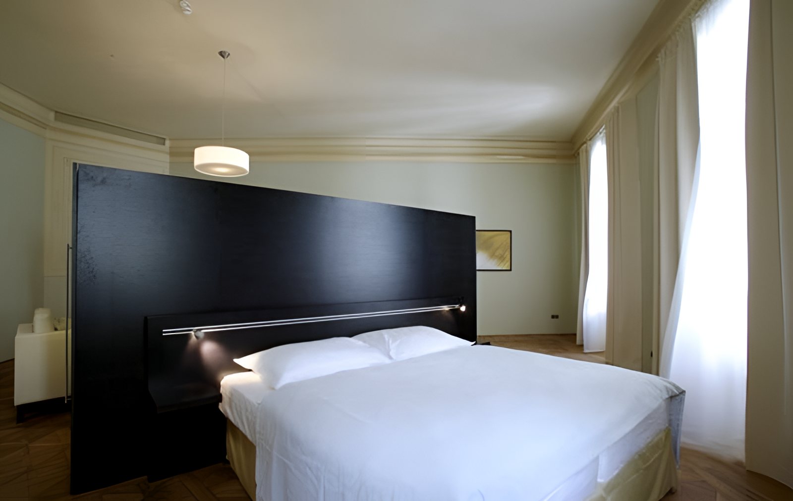 Hotelová ložnice s tmavým čelem postele